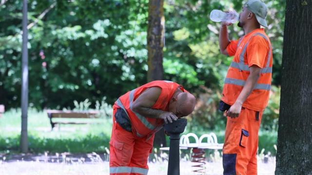 Dos trabajadores se refrescan en plena ola de calor.