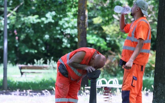 Dos trabajadores se refrescan en plena ola de calor.