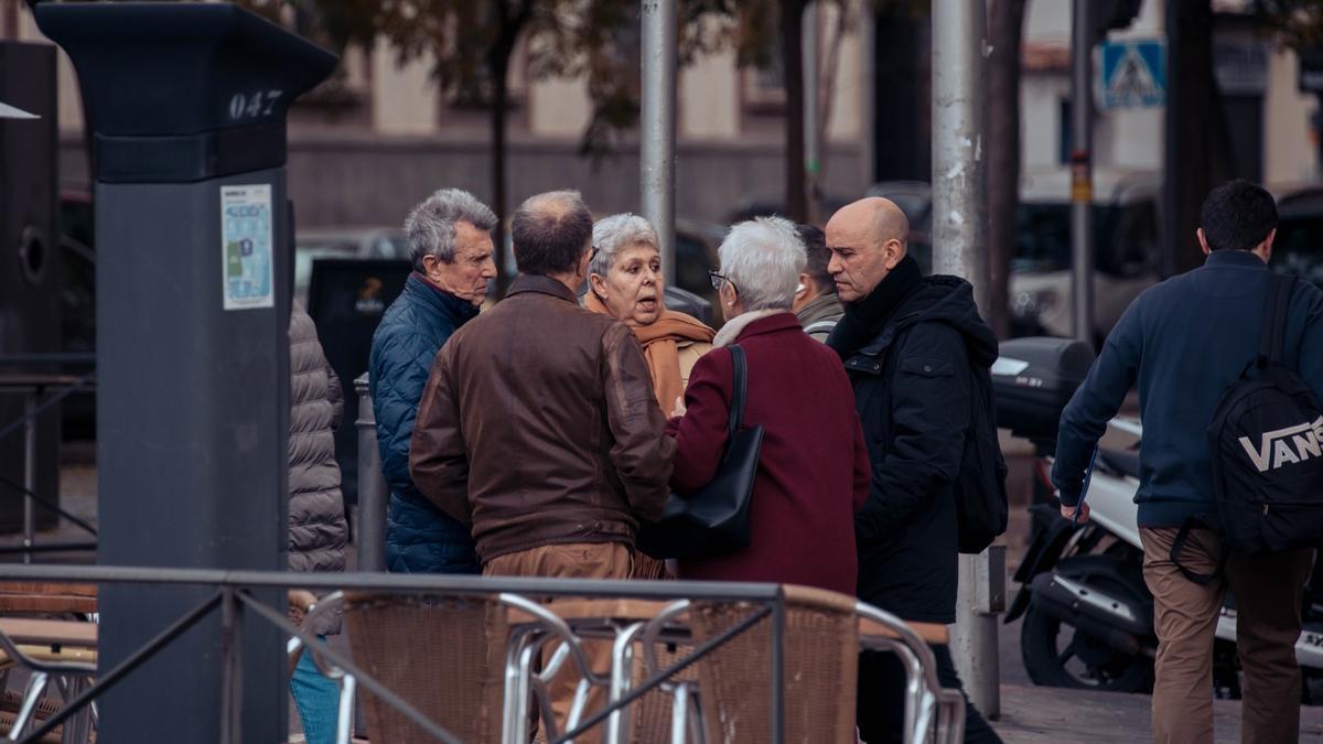 Varios jubilados conversan en la calle.
