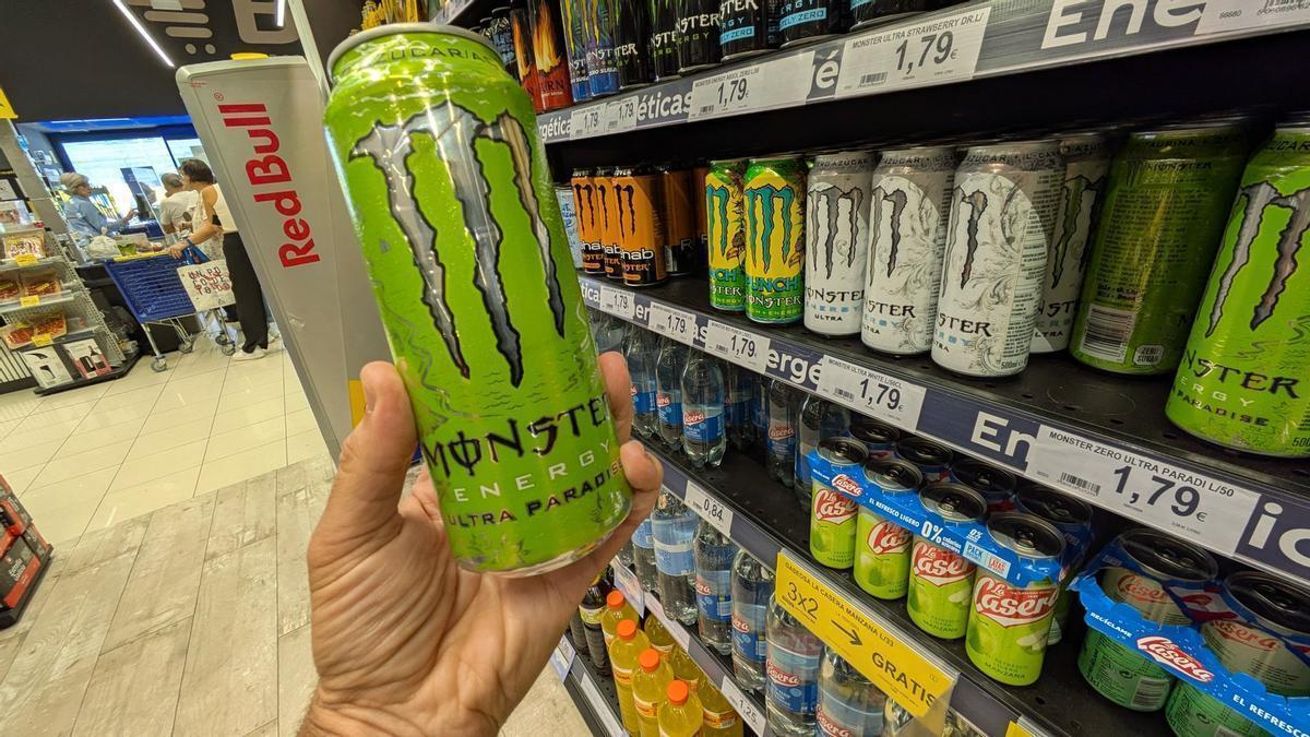 Un cliente de un supermercado coge una lata de la estantería de las bebidas energéticas.