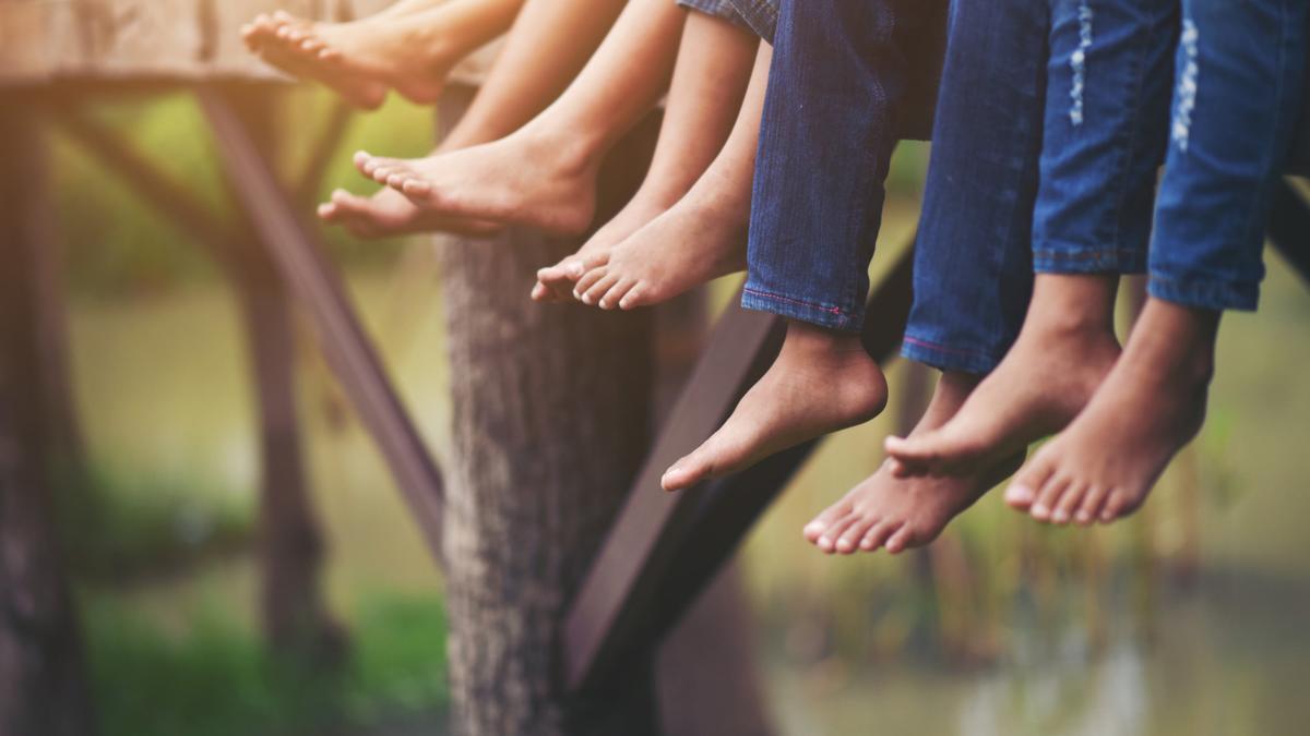 Varias personas posan al aire libre con los pies descalzos.