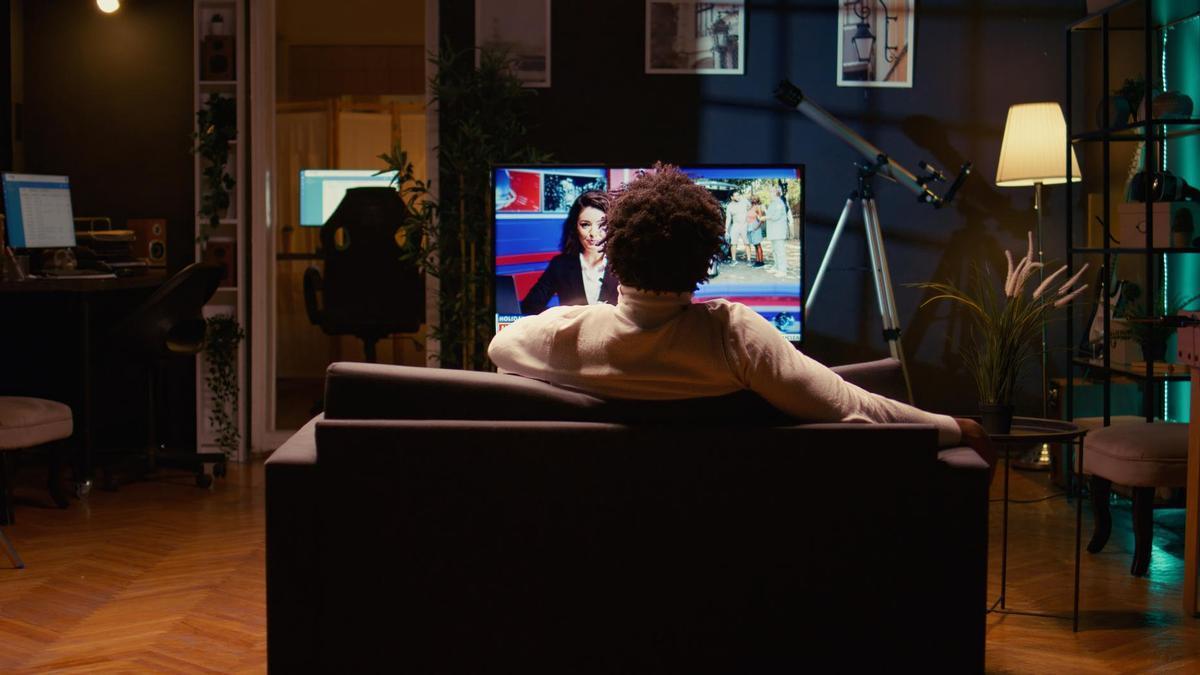 Una persona ve la televisión en el salón de su casa.