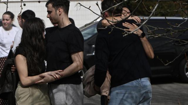 Varias personas, durante el minuto de silencio en homenaje a los estudiantes fallecidos en el derrumbe de una pasarela costera de Santander.