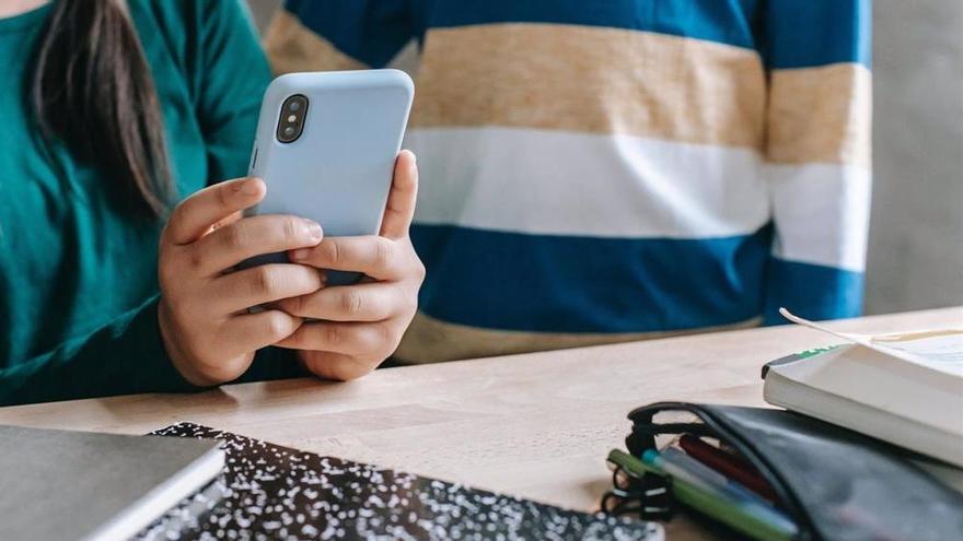 Menores consultado un teléfono móvil.