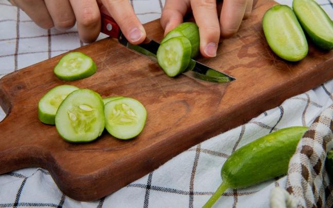 Un cocinero corta un pepino en ruedas gruesas.