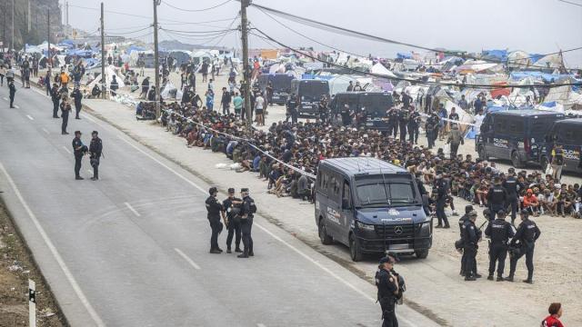 Agentes de la Policía Nacional intervienen durante el proceso de desalojo del embolsamiento de migrantes en la playa de El Trampolín en Ceuta.