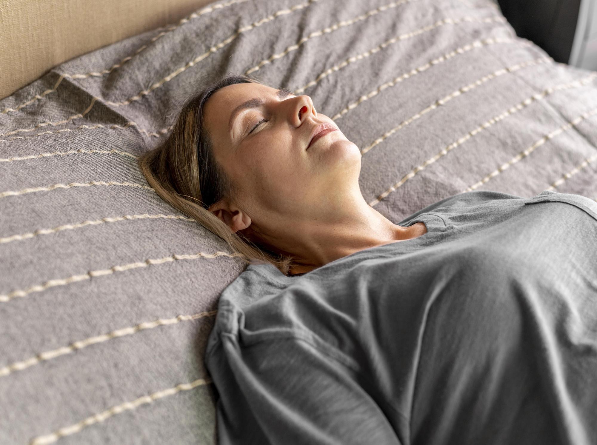 Mujer practica técnicas de respiración para relajarse antes de dormir.