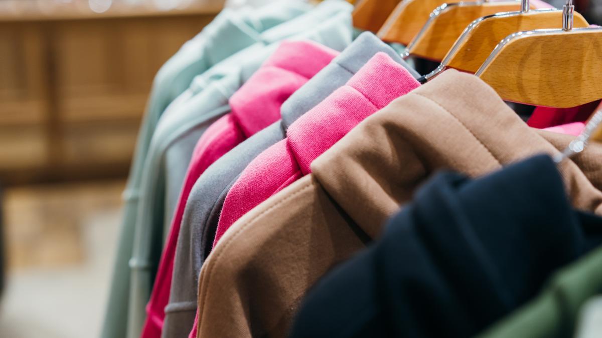 Sudaderas colgadas en perchas de madera.