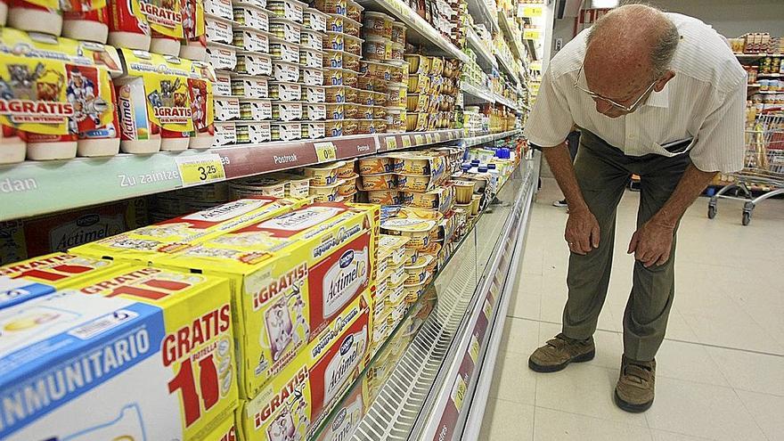 Un hombre se fija en el precio de los yogures de un supermercado.