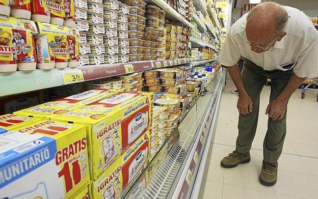 Un hombre se fija en el precio de los yogures de un supermercado.
