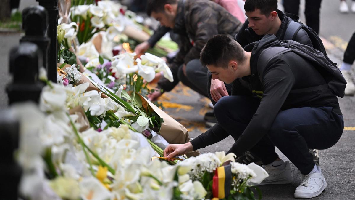 Varios jóvenes depositan flores en el lugar donde se ha producido un tiroteo masivo en Serbia.