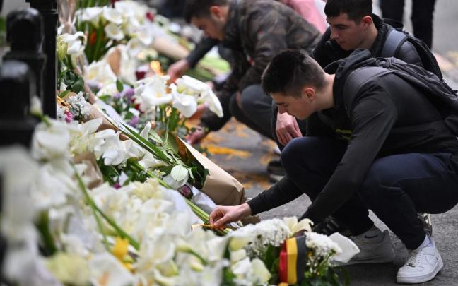 Varios jóvenes depositan flores en el lugar donde se ha producido un tiroteo masivo en Serbia.