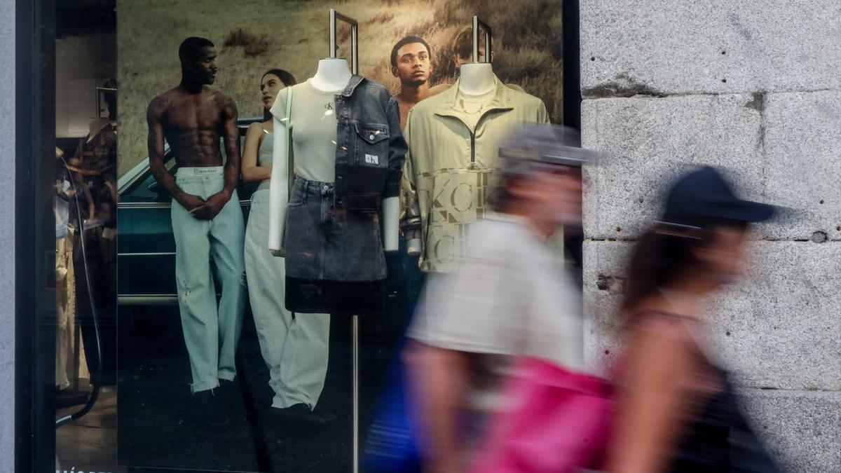 Varias personas caminan por delante del escaparate de un comercio.