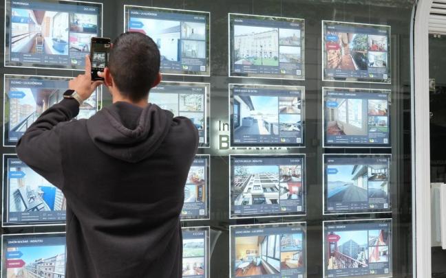 Un joven fotografía las ofertas en el escaparate de una inmobiliaria de Bilbao.