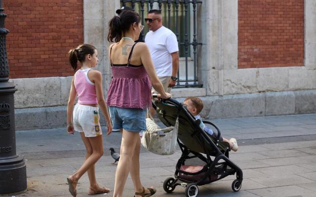 Una mujer pasea con dos niños.