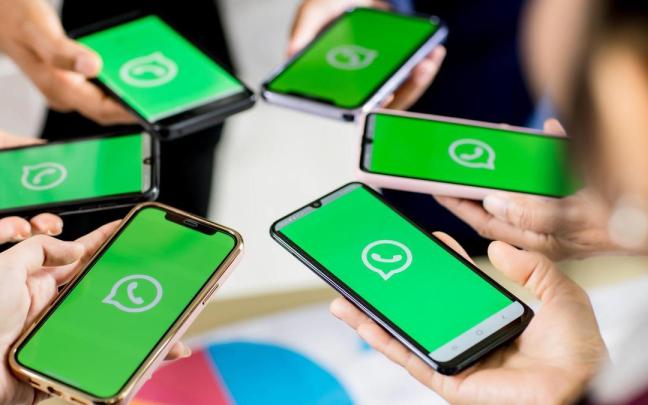 Un grupo de persinas abre la aplicaciónde WhatsApp en sus móviles.