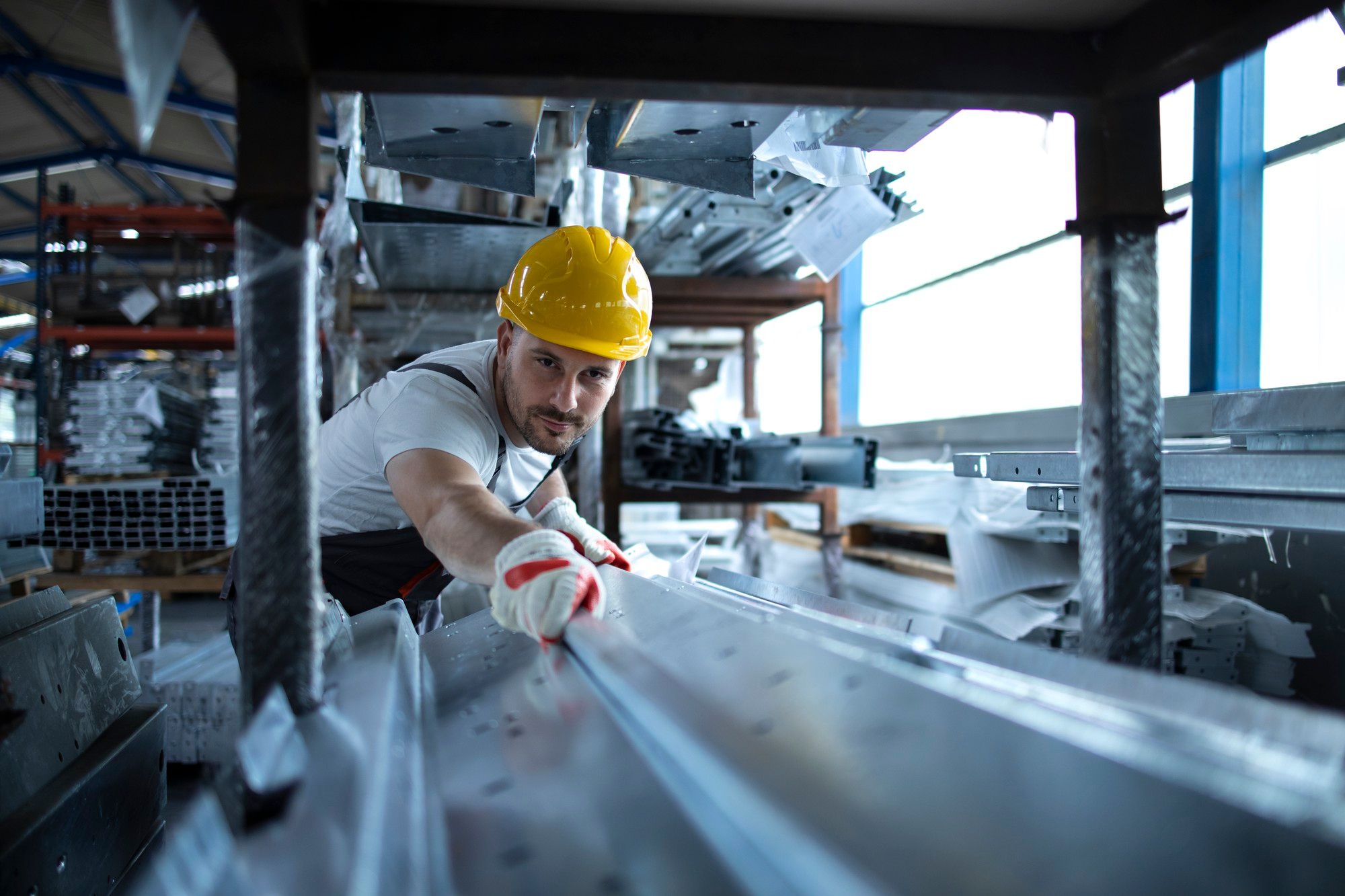 Un trabajador de una fábrica manipula material metálico.