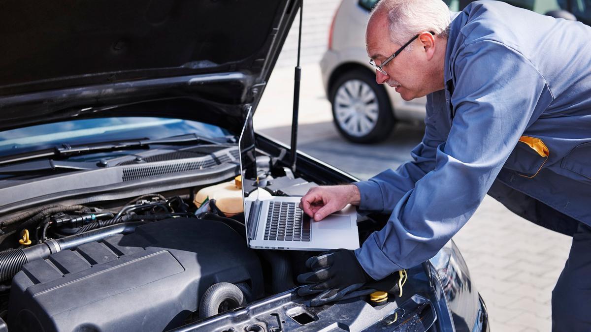 Un mecánico registra en un portátil los datos de telemetría de un coche.