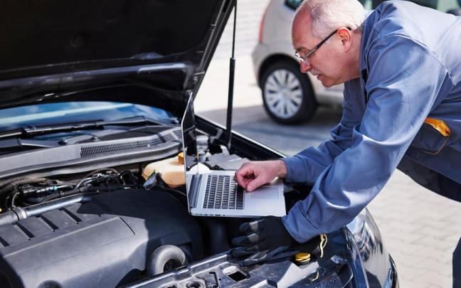 Un mecánico registra en un portátil los datos de telemetría de un coche.