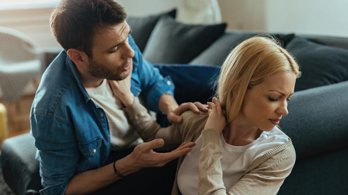Una joven pareja, visiblemente disgustada, discute en casa sobre sus problemas de pareja.