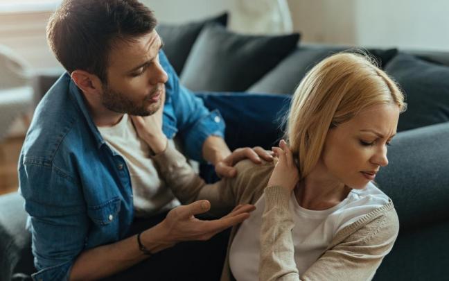 Una joven pareja, visiblemente disgustada, discute en casa sobre sus problemas de pareja.