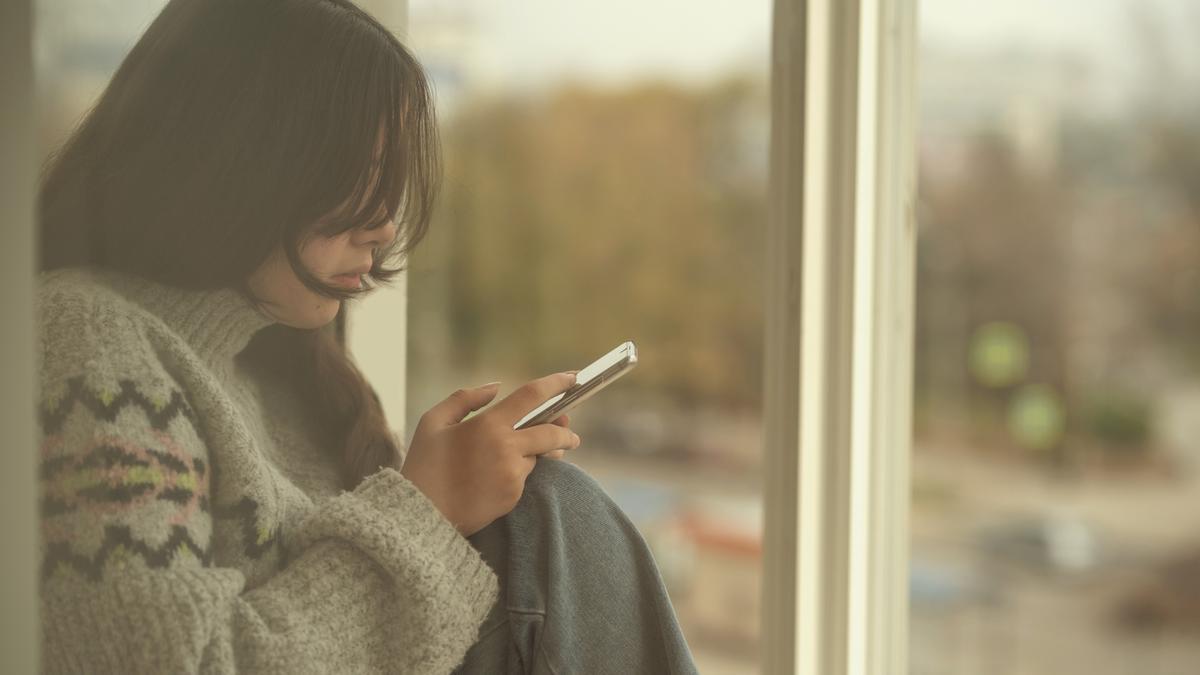 Una joven sola, utilizando su teléfono móvil.