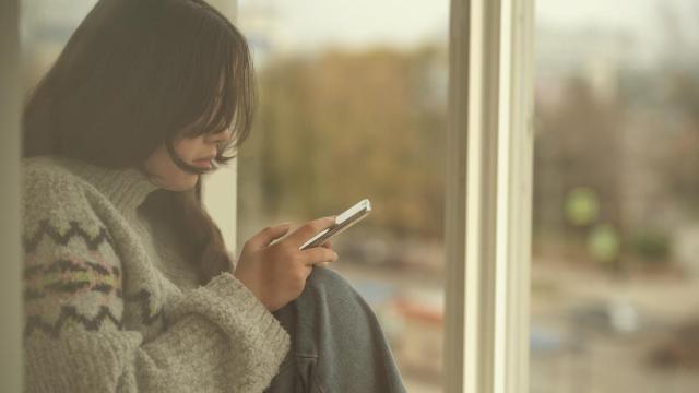Una joven sola, utilizando su teléfono móvil.