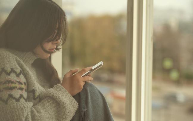 Una joven sola, utilizando su teléfono móvil.