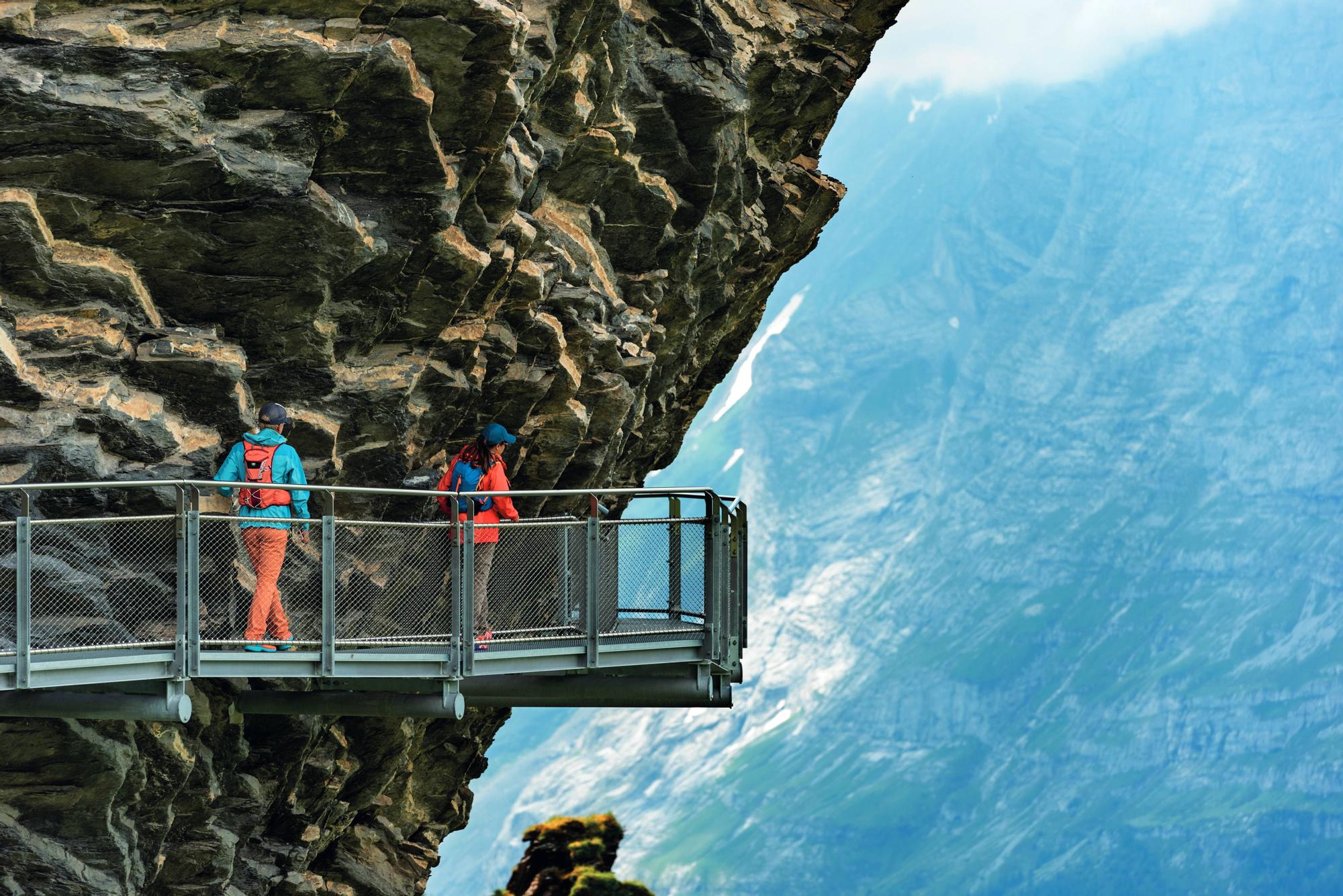 Dos excursionistas en la pasarela junto al acantilado del First Cliff Walk por Tissot.