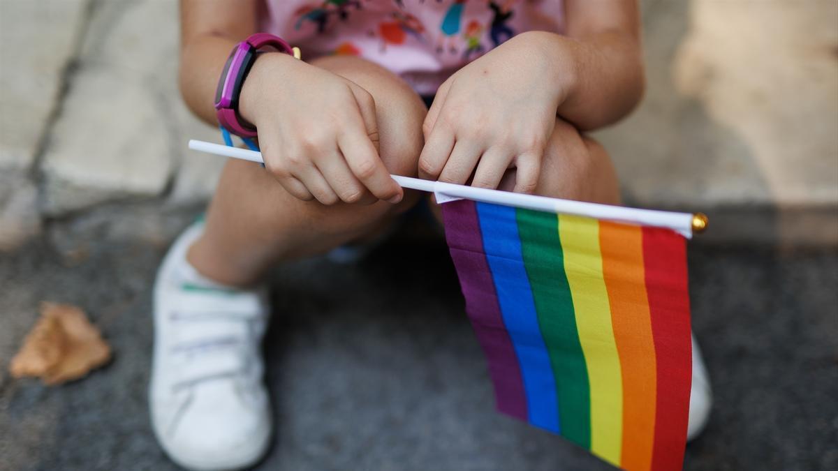 Una niña sostiene la bandera del arcoiris.