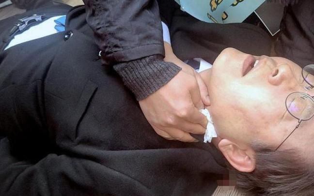 Lee Jae-myung es atendido en el suelo tras recibir la puñalada.