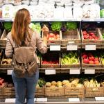 Una mujer elige entre varias verduras en un supermercado.