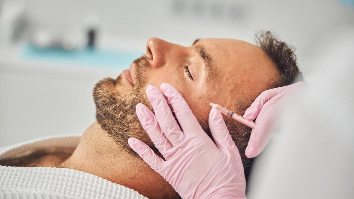 Especialista realiza una infiltración de ácido hialurónico para redefinir los rasgos faciales de un paciente.