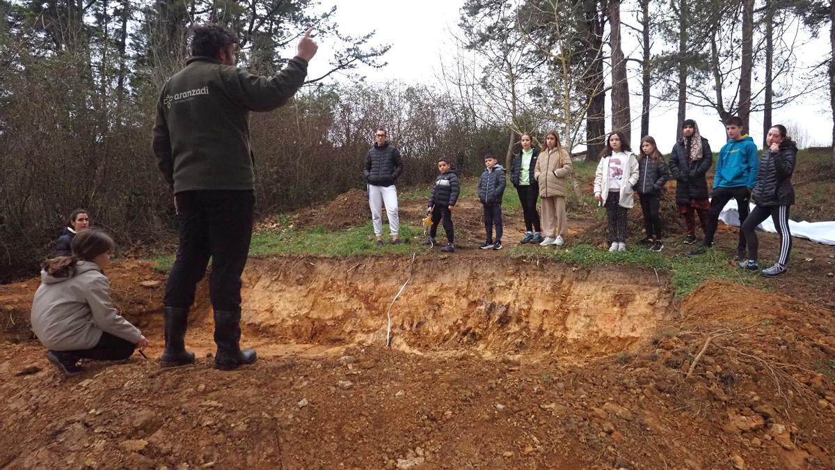 Jon Garin, miembro de la Sociedad de Ciencias Aranzadi, explicando a los escolares la labor que tienen que llevar a cabo para preparar el estanque.