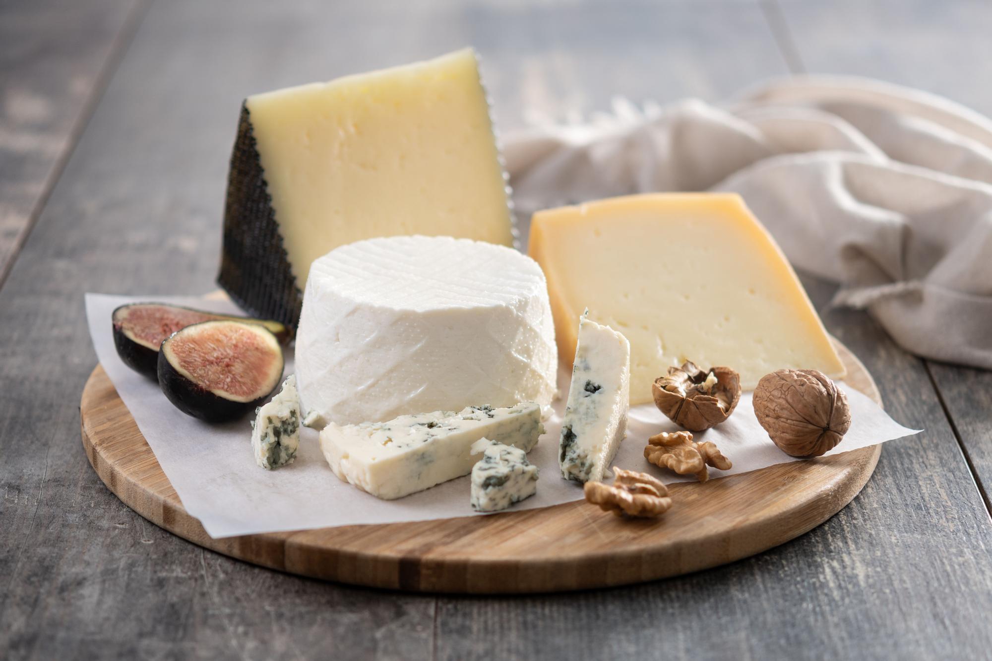 Surtido de quesos gourmet con higos y nueces en una tabla de madera.