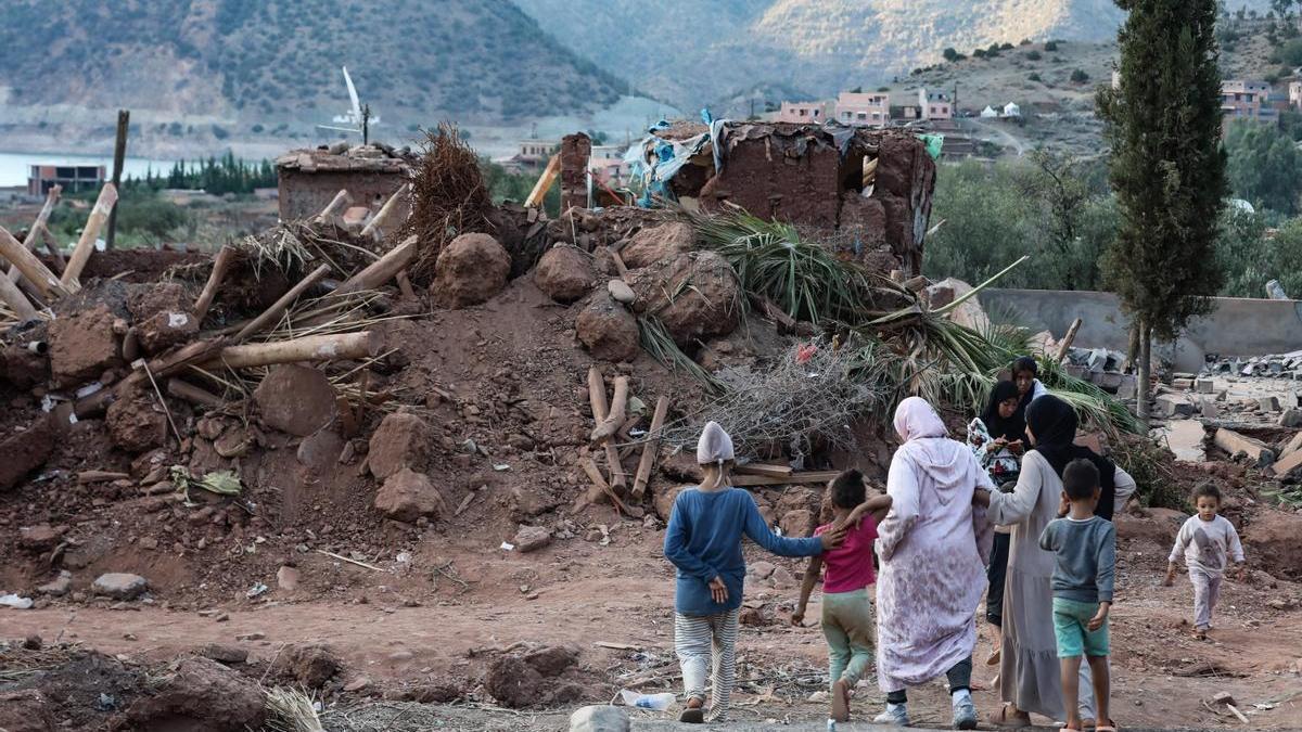 Un grupo de mujeres y niños junto a los escombros de una vivienda en Al Haouz, Marruecos.