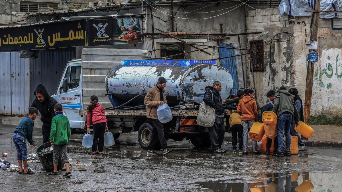 Un grupo de palestinos llena varias garrafas de agua potable en Rafah.