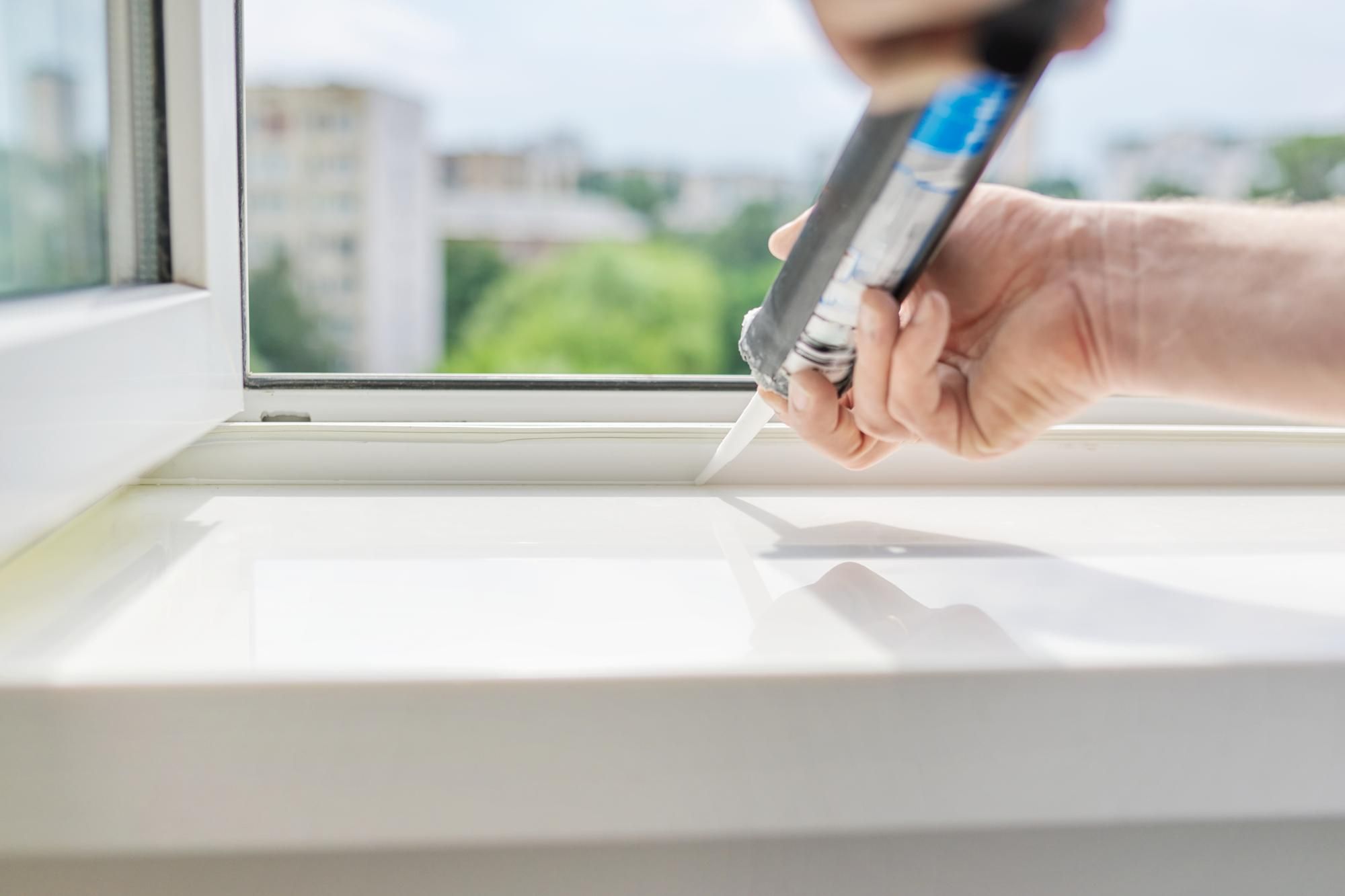 Un trabajador aplica silicona para sellar el marco de una ventana.
