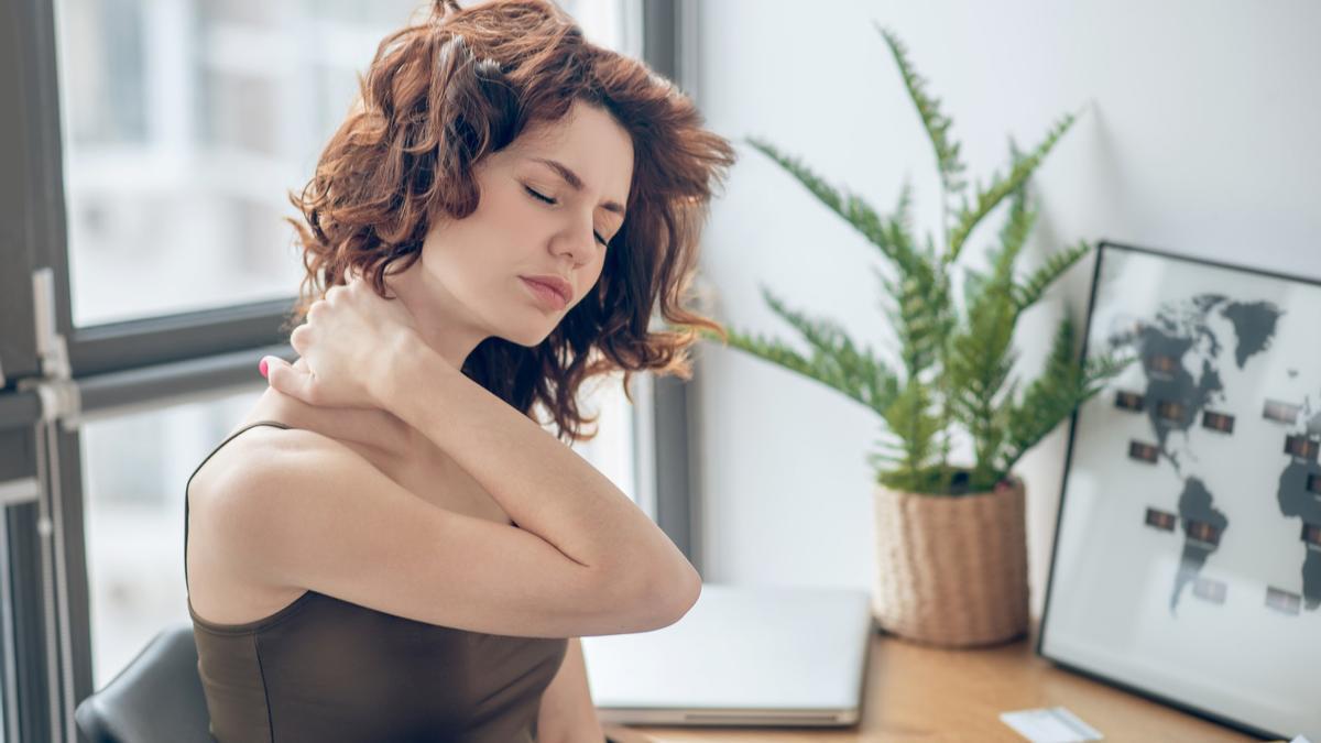 Una mujer con un fuerte dolor en el cuello.