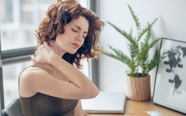 Una mujer con un fuerte dolor en el cuello.
