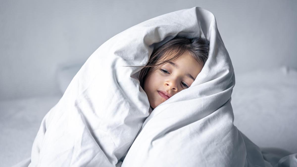 Una niña se cubre con un edredón nórdico.