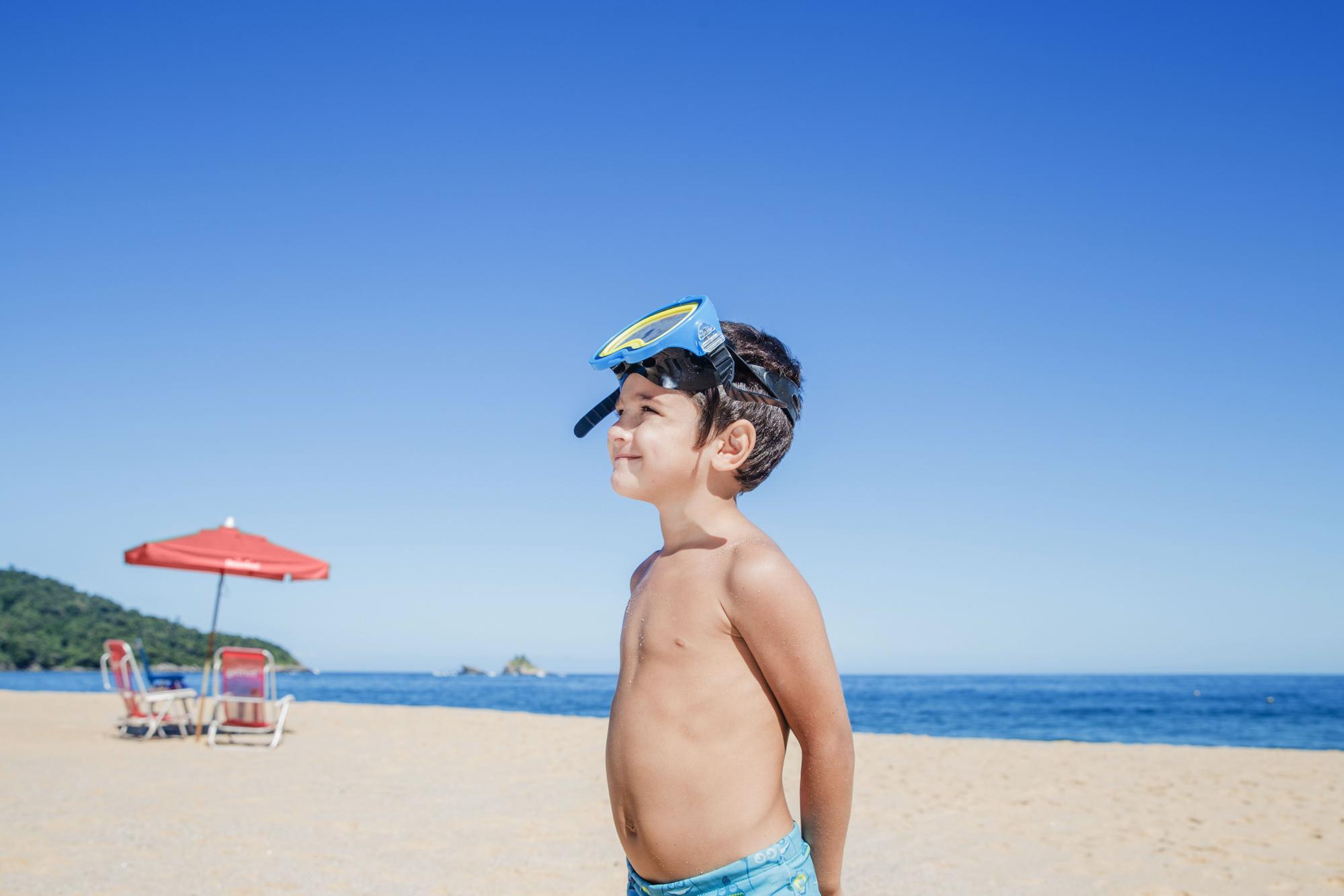 Niño con gafas de bucear juega en la playa.