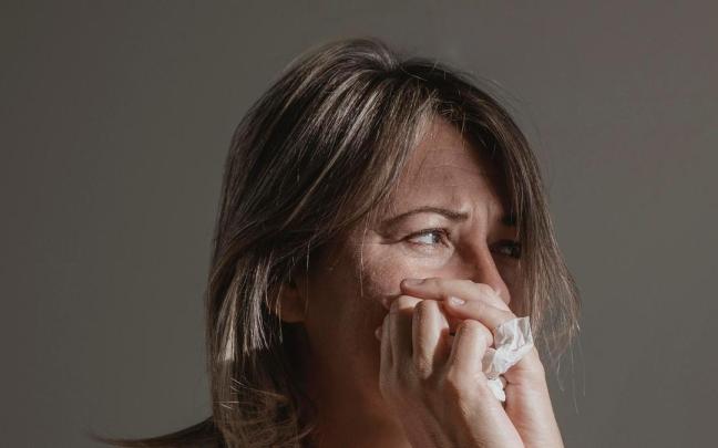 Una mujer sujeta un pañuelo entre sus manos para secarse las lágrimas.