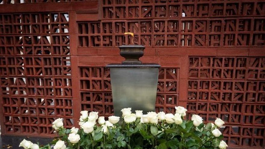 Ofrenda floral y pebetero encendido ante a escultura 'Gauerdiko Iparrorratza-Brújula de Medianoche', una obra dedicada a las víctimas.