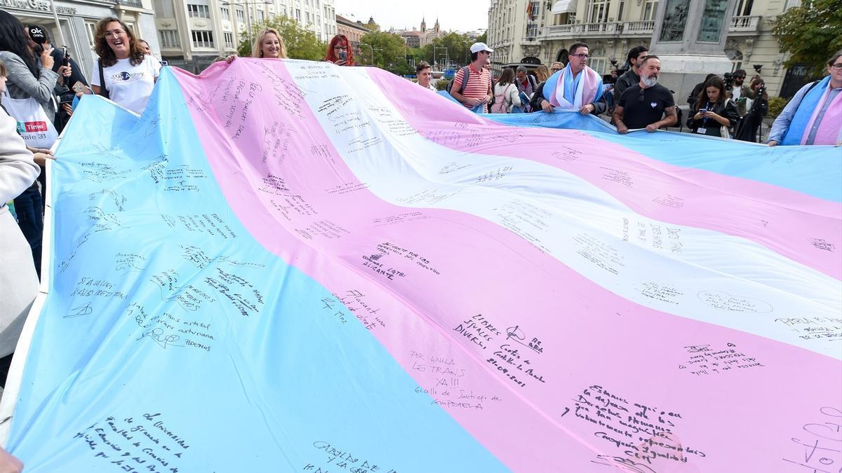 Varias personas sosteniendo la bandera trans en una foto de archivo.