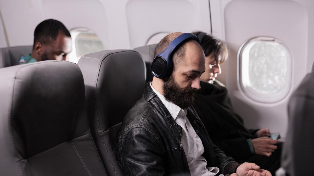 Pasajero de un avión con auriculares escucha música durante el vuelo.