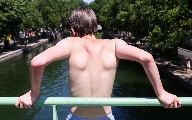 Un joven se refresca en París ante las altas temperaturas.