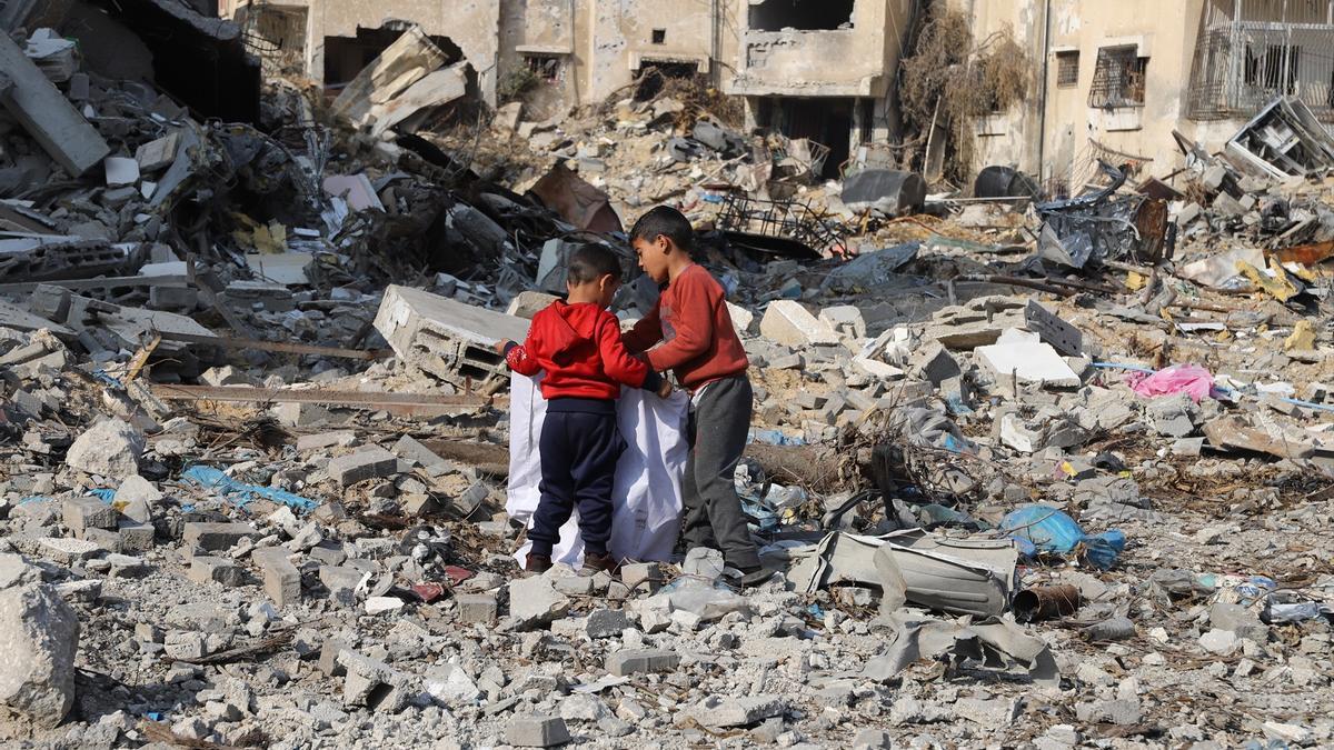 Dos niños palestinos buscan enseres entre los escombros tras un bombardeo israelí.
