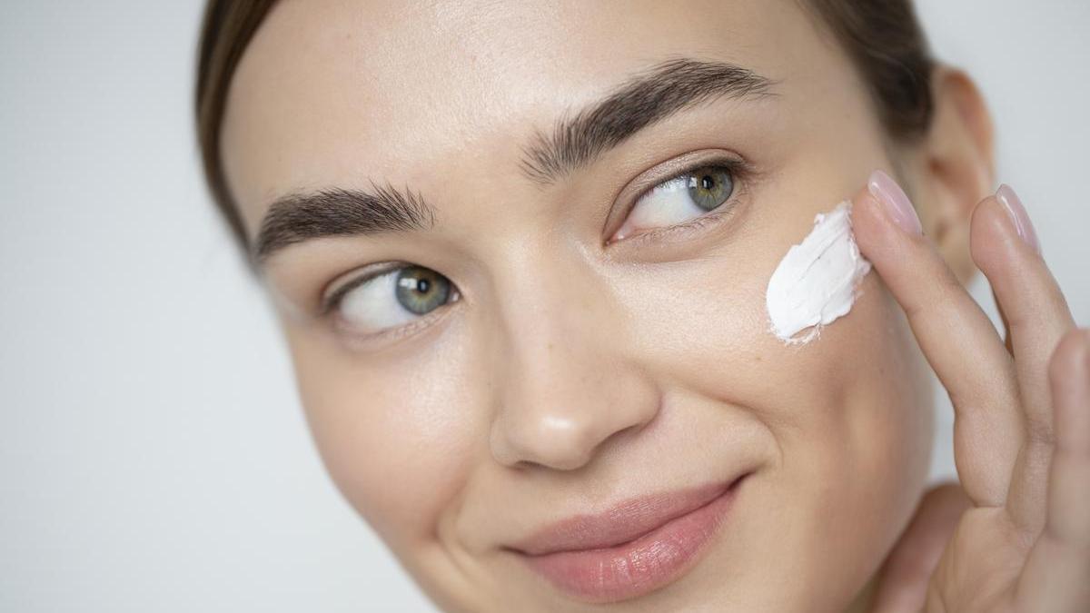Chica se aplica protección solar en el rostro antes de salir de casa.