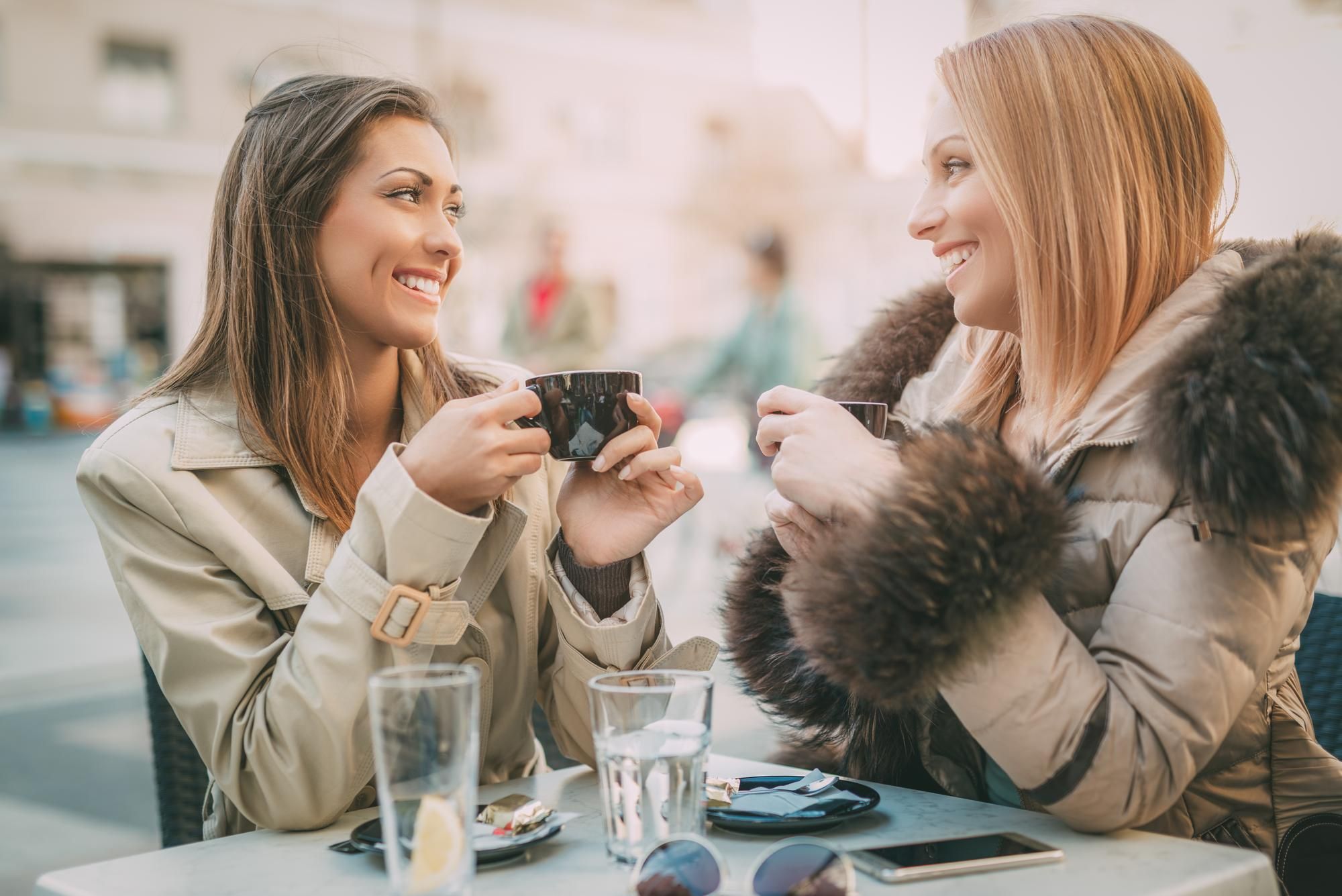 Dos amigas comparten un café en una terraza.